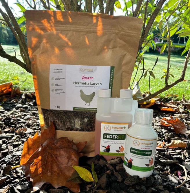 Mauserset steht im herbstlichen Garten, eine große Tüte Hermetia Larven, eine Pumpflasche Federfit und eine Flasche DermaCare